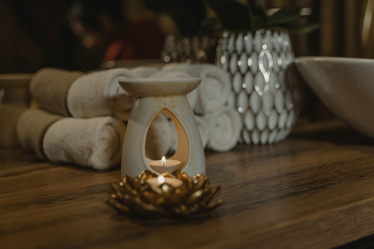 Candle diffuser glowing beside rolled towels in the spa room